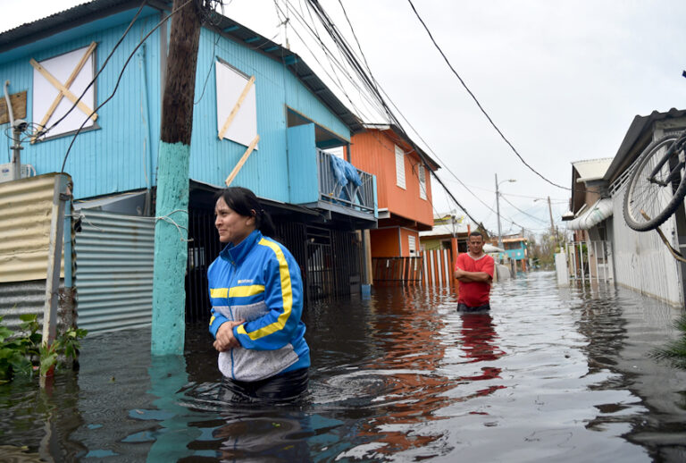 People walk across a flooded street in Juana Matos, Puerto Rico, on September 21, 2017 as the country faced dangerous flooding and an island-wide power outage following Hurricane Maria. (Getty/Hector Retamal)