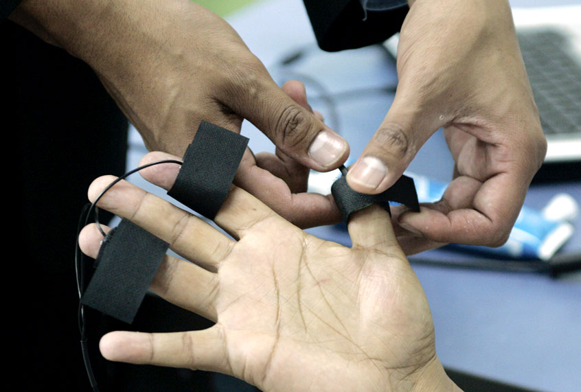 A polygraph examiner applies electrodes on the fingers of a student. (AP/Fernando Vergara)