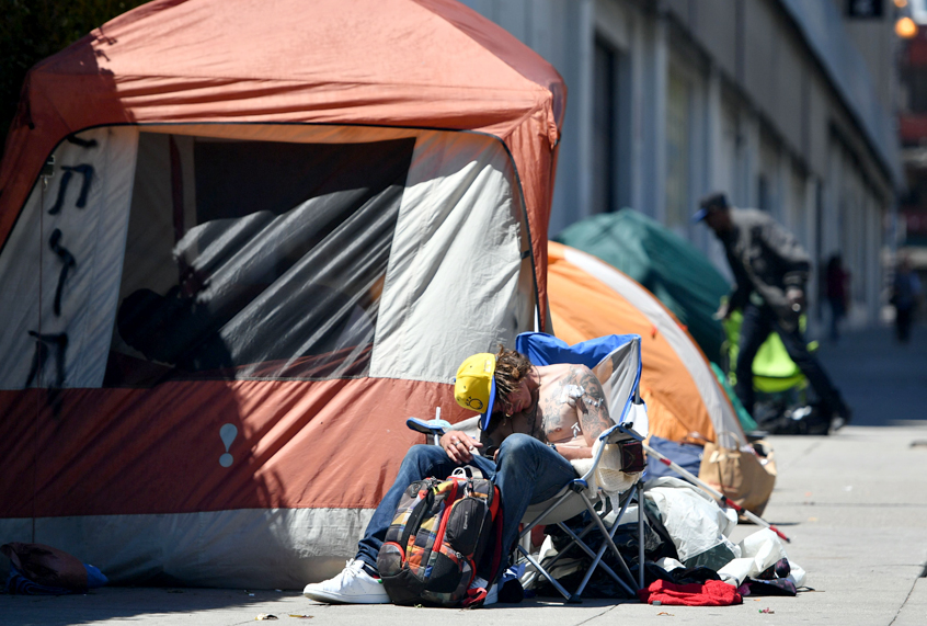 A homeless man sleeps in front of his tent along Van Ness Avenue in downtown San Francisco, California on June, 27, 2016. (Getty/Josh Edelson)