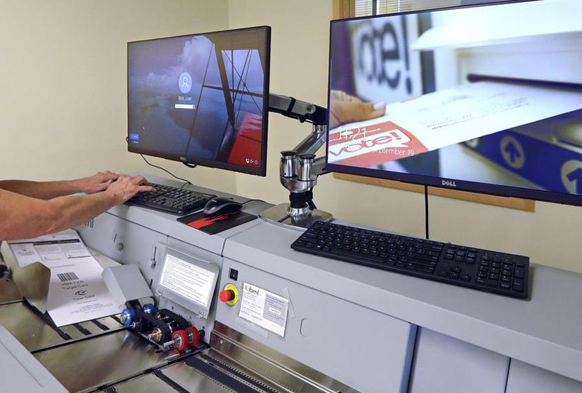 Election worker Kelly Moselage puts test ballots through a vote counting machine at the King County Elections office in Renton, Wash., Sept. 19, 2018 (AP/Elaine Thompson)