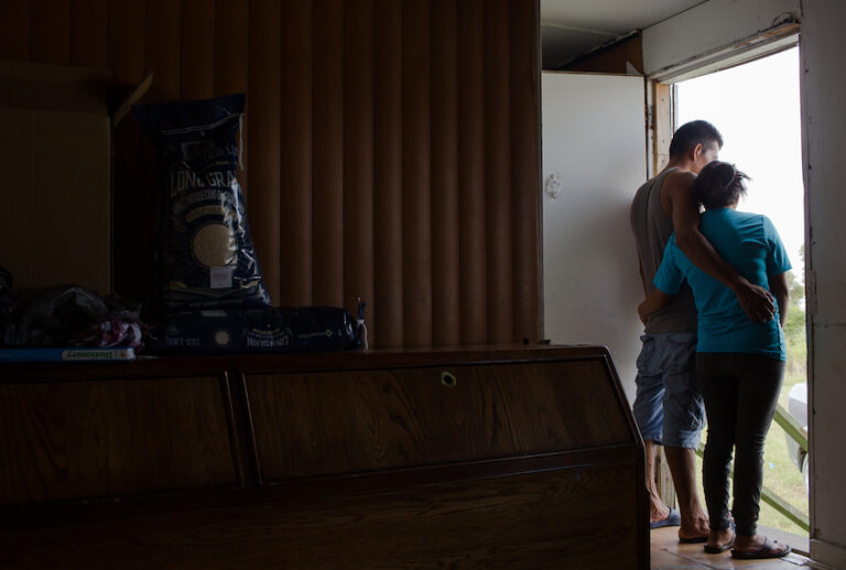 A farmworker couple, Nelson and Silvia* from Guatemala, surveys the flooding outside of their North Carolina trailer home after Hurricane Florence. (Justin Cook)
