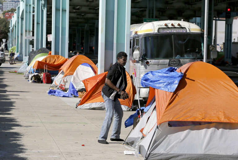 A man stands outside his tent on Division Street in San Francisco. (AP/Eric Risberg)