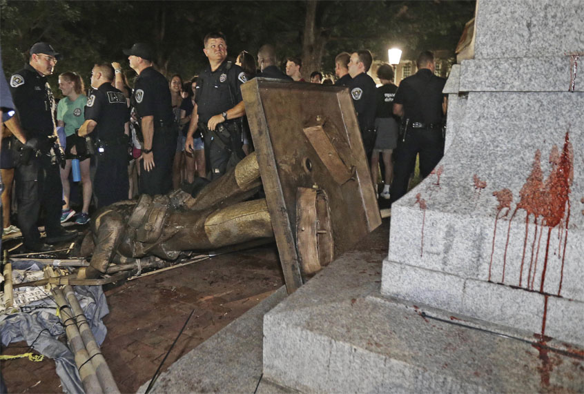 FILE - In this Aug. 20, 2018, file photo, police stand guard after the confederate statue known as Silent Sam was toppled by protesters on campus at the University of North Carolina in Chapel Hill, N.C. Leaders of North Carolina’s flagship university are meeting to decide the fate of a Confederate monument torn down by protesters. The chancellor and trustees of the University of North Carolina at Chapel Hill were finalizing a plan Monday, Dec. 3, for the century-old bronze statue known as “Silent Sam.” (AP Photo/Gerry Broome, File) (AP)