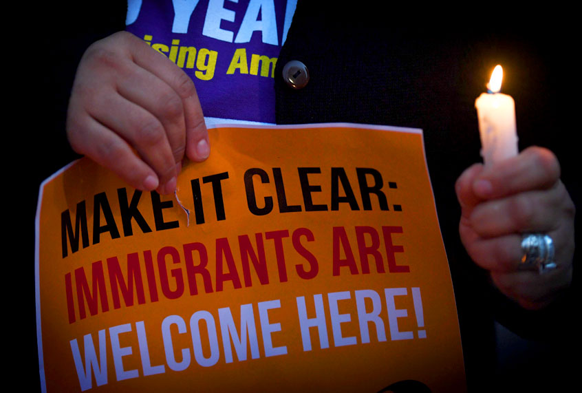 Migrant rights groups hold candles during a vigil to protest against US President Donald Trump's new crackdown on sanctuary cities. (Getty/Mark Ralston)