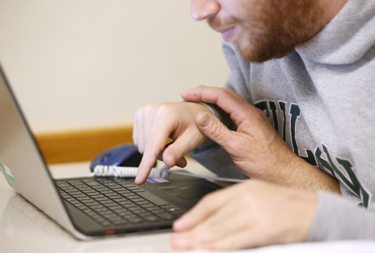 Sam Alexander, Ben Alexander's father, assists Ben during a math language class at Tulane University in New Orleans. Ben Alexander, 22, has nonverbal autism, a condition that became apparent when he was 2 years old. (AP/Jonathan Bachman)