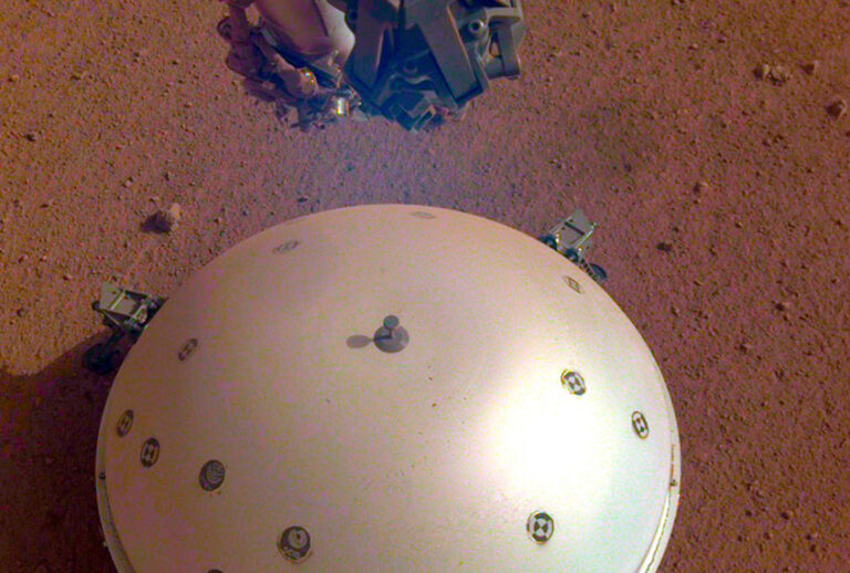 This photo made available by NASA on Tuesday, April 23, 2019 shows the InSight lander's domed wind and thermal shield which covers a seismometer on the 110th Martian day, or sol, of the mission. On Tuesday, the space agency announced the instrument picked up a gentle rumble, believed to be the first marsquake ever detected. (NASA/JPL-Caltech via AP)
