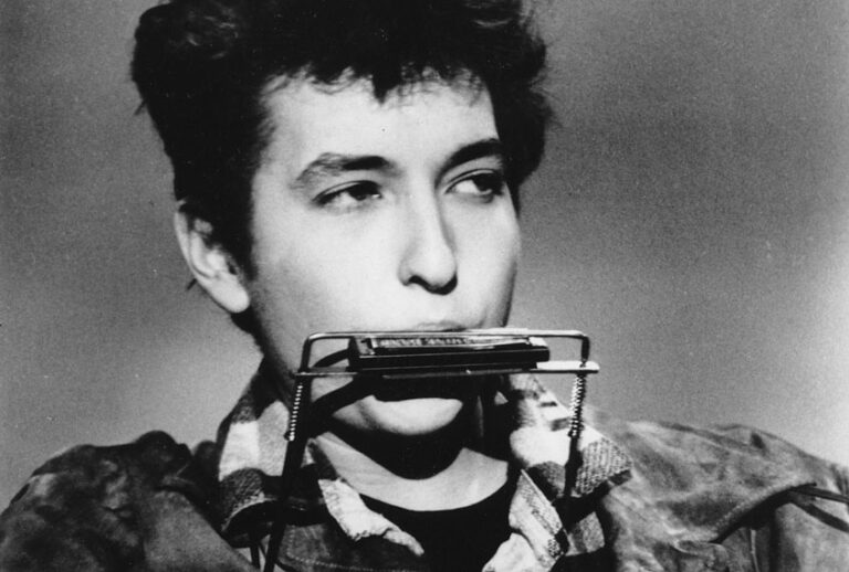 Bob Dylan plays the harmonica and acoustic guitar in March 1963 at an unknown location. (AP Photo)