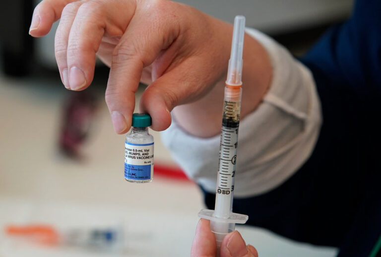 A nurse holds up a one dose bottle and a prepared syringe of measles, mumps and rubella virus vaccine. (Getty/George Frey)