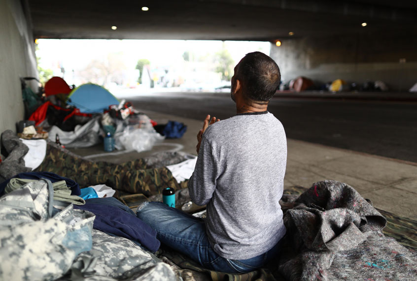 Travis Stanley, who said he has been homeless for three months and is a U.S. Navy veteran, sits on donated bedding, where he normally sleeps, beneath an overpass on June 5, 2019 in Los Angeles, California. (Getty/Mario Tama)