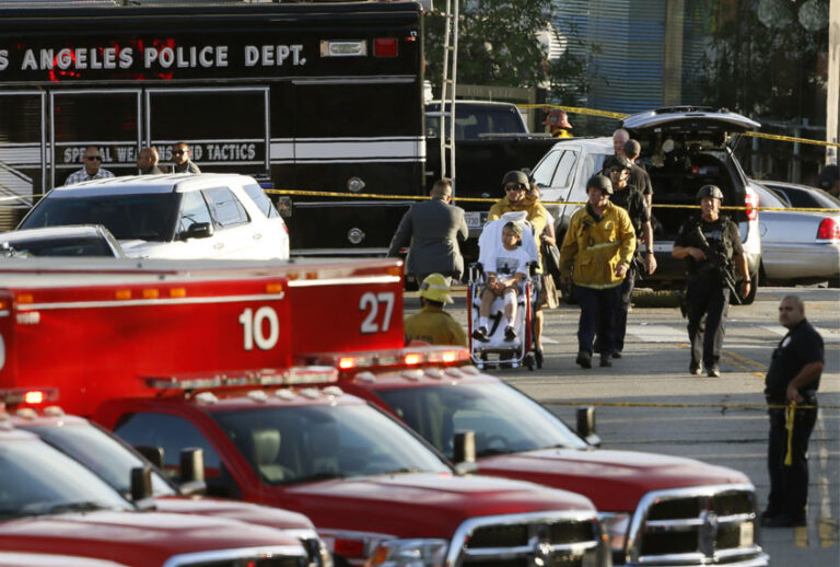 Los Angeles Police SWAT officers, and Los Angeles firemen wearing bulletproof helmets, evacuate a child, after a gunman barricaded himself inside a Trader Joe's store in Los Angeles, July 21, 2018. (AP/Damian Dovargane)