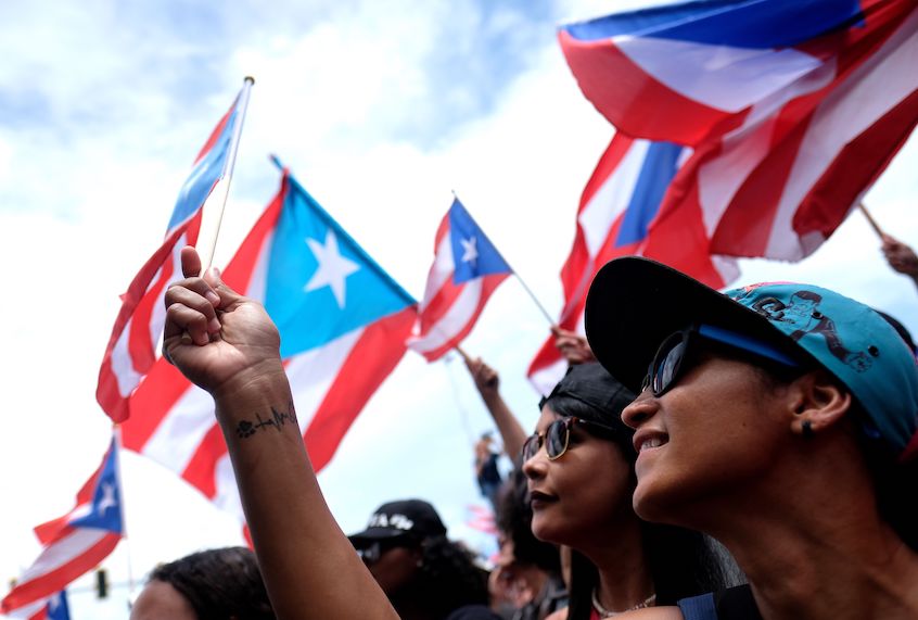 Demonstrators wave flags as they participate in a march the day after the governor of Puerto Rico, Ricardo Rossello, resigned from his charge in San Juan, on July 25, 2019. (Ricardo Arduengo/AFP/Getty Images)