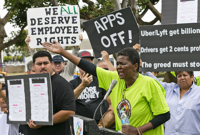 Uber driver Estaphanie St. Just joins drivers for ride-hailing giants Uber and Lyft, as they hold a rally at a park near Los Angeles International Airport, Wednesday, May, 8, 2019, in Los Angeles. (AP Photo/Damian Dovarganes)