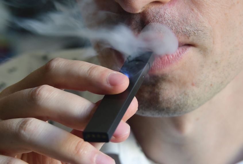 An illustration shows a man exhaling smoke from an electronic cigarette in Washington, DC on October 2, 2018. - In just three years, the electronic cigarette manufacturer Juul has swallowed the American market with its vaporettes in the shape of a USB key. Its success represents a public health dilemma for health authorities in the United States and elsewhere. (Photo by EVA HAMBACH / AFP)        (Photo credit should read EVA HAMBACH/AFP/Getty Images) (Eva Hambach/AFP/Getty Images)
