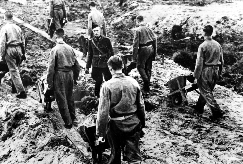 Prisoners of the Dutch Labor Corps work in chain gang fashion under a Nazi foreman in a forced labor camp in the Netherlands, March 2, 1944 during World War II. (AP Photo)