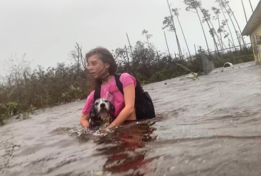 Julia Aylen wades through waist deep water carrying her pet dog as she is rescued from her flooded home during Hurricane Dorian in Freeport, Bahamas, Tuesday, Sept. 3, 2019. (AP Photo/Tim Aylen)