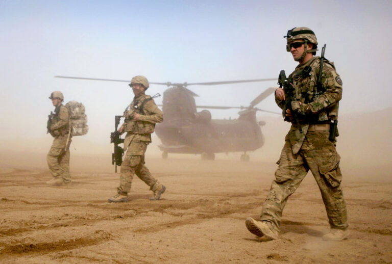 In this Saturday, Jan. 28, 2012 file photo, U.S. soldiers, part of the NATO- led International Security Assistance Force (ISAF) walks, as a U.S. Chinook helicopter is seen on the back ground near the place where the foundation of a hospital was laid in Shindand, Herat, west of Kabul, Afghanistan. (AP Photo/Hoshang Hashimi)