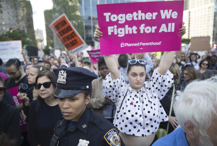 A New York City police officer stands guard nest to demonstrator Juliette Proctor during a protest against abortion bans, Tuesday, May 21, 2019, in New York. (AP Photo/Mary Altaffer)