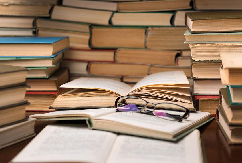 Open book and glasses on wood desk in the library room (Getty Images/  Konstantin Maslak)
