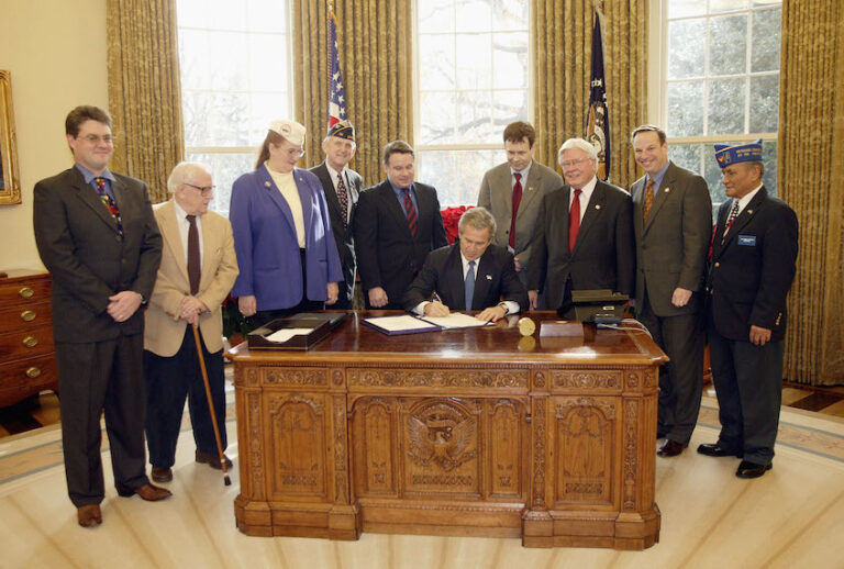 WASHINGTON - DECEMBER 16:  U.S. President George W. Bush signs H. R. 2297, the Veterans Benefits Act of 2003, in the White House Oval Office December 16, 2003 in Washington, DC. The act will expand the benefits program for veterans and their surviving spouses. Also present were (L to R) veterans Dave Thornton of Haymarket, Virginia, Charles Stenger of Bethesda, Maryland, Carol Near of East Moline, Illinois, Congressman Rob Simmons (R-CT), Congressman Lane Evans (D-IL), Congressman Henry Brown (R-SC), Congressman Bob Filner (D-CA) and veteran Guillermo Rumingan of Arlington, Virginia.  (Photo by Paul Morse/White House via Getty Images) ((Photo by Paul Morse/White House via Getty Images)