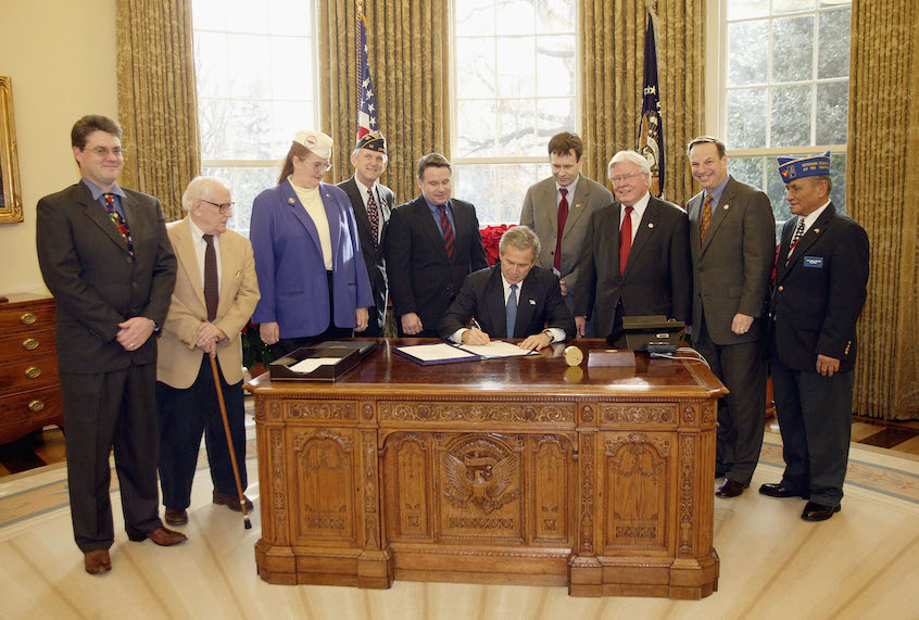 WASHINGTON - DECEMBER 16:  U.S. President George W. Bush signs H. R. 2297, the Veterans Benefits Act of 2003, in the White House Oval Office December 16, 2003 in Washington, DC. The act will expand the benefits program for veterans and their surviving spouses. Also present were (L to R) veterans Dave Thornton of Haymarket, Virginia, Charles Stenger of Bethesda, Maryland, Carol Near of East Moline, Illinois, Congressman Rob Simmons (R-CT), Congressman Lane Evans (D-IL), Congressman Henry Brown (R-SC), Congressman Bob Filner (D-CA) and veteran Guillermo Rumingan of Arlington, Virginia.  (Photo by Paul Morse/White House via Getty Images) ((Photo by Paul Morse/White House via Getty Images)