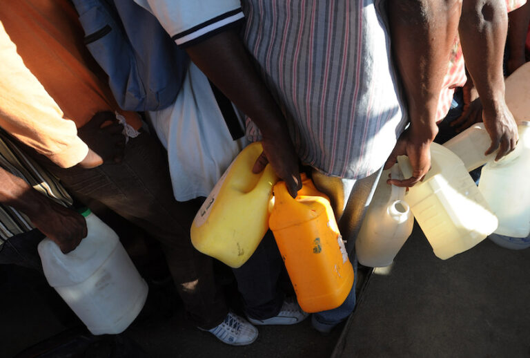 Haitian men queue for gasoline at a fueling station in Port-au-Prince on January 17, 2010, five days after a massive quake destroyed much of the city. Thousands living in the streets of Haiti's capital face a "desperate" situation and hospitals are overwhelmed by masses of people injured in the deadly earthquake, the international Red Cross said Sunday.  AFP   PHOTO/Juan BARRETO (Photo credit should read JUAN BARRETO/AFP/Getty Images) (Juan Barreto/AFP/Getty Images)
