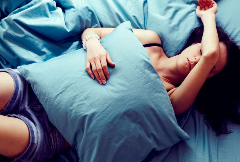 Depressed woman in bed with hand on forehead (Getty/ Martin Dimitrov)