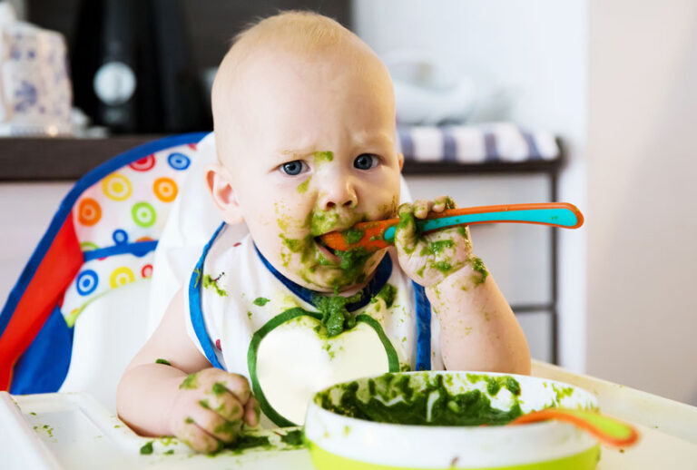 Baby eating green mush baby food (Getty Images/iStock)