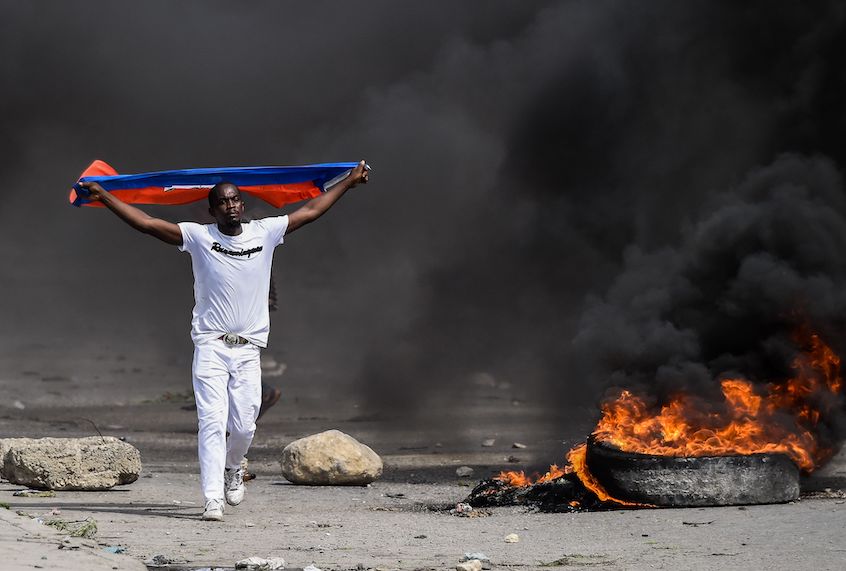 A demonstrator waves a Haitian flag during a protest outside United Nation's main base, against President Jovenel Moise on October 4, 2019 in Port-au-Prince, Haiti. (Chandan Khanna//AFP via Getty Images)