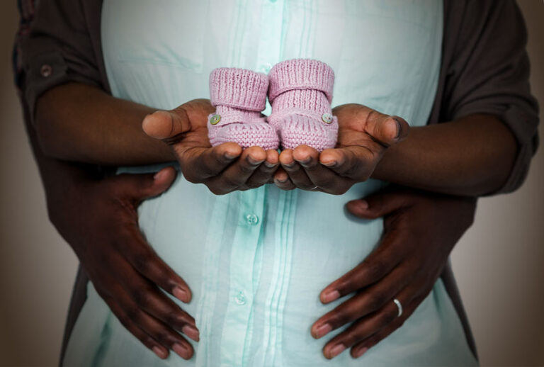 Pregnant couple holding baby shoes (Getty Images/Salon)
