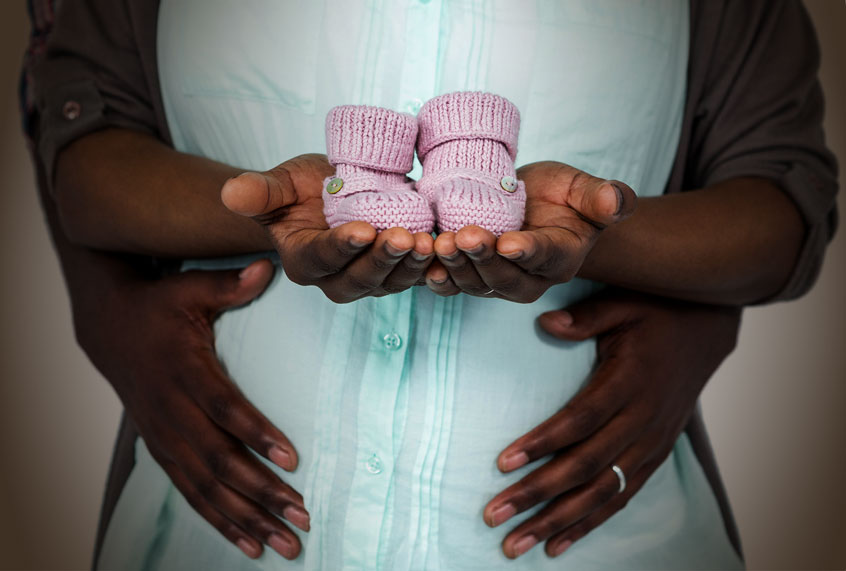 Pregnant couple holding baby shoes (Getty Images/Salon)