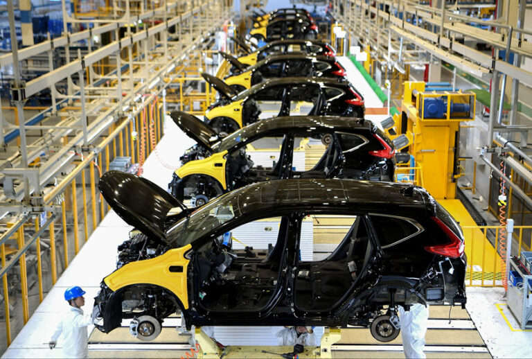 Employees working on an assembly line at an Auto Plant (STR/AFP via Getty Images)