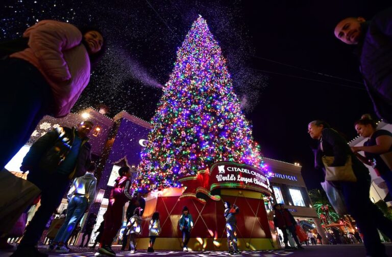 Children get excited by the artificial snow spewing from the "World's Tallest live-cut Christmas Tree," standing 115 feet and decorated with some 18,000 multi-colored LED lights, at the Citadel Outlets shopping plaza in Los Angeles, California on December 17, 2019. (Photo by Frederic J. BROWN / AFP) (Photo by FREDERIC J. BROWN/AFP via Getty Images) (Frederic J. Brown/AFP via Getty Images)