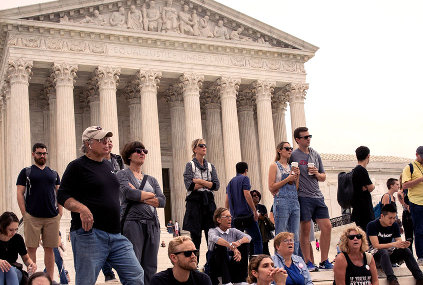 People sit on the steps of the Supreme Court as they watch protesters rally against the confirmation of Supreme Court nominee Judge Brett Kavanaugh, outside of the Supreme Court, October 6, 2018 in Washington, DC. The Senate is set to hold a final vote Saturday evening to confirm the nomination of Judge Brett Kavanaugh to the U.S. Supreme Court. (Drew Angerer/Getty Images)