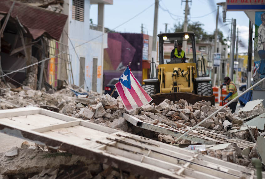 A Puerto Rican flag waves on top of a pile of rubble as debris is removed from a main road in Guanica, Puerto Rico on January 8, 2020. (Ricardo Arduengo/AFP via Getty Images)