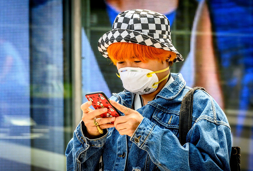 A woman wearing a protective facemask checks her mobile phone outside a shopping mall in Bangkok on February 4, 2020. - Thailand so far has detected 19 confirmed cases of the novel coronavirus believed to have originated in the central Chinese city of Wuhan, which is under lockdown. (MLADEN ANTONOV/AFP via Getty Images)