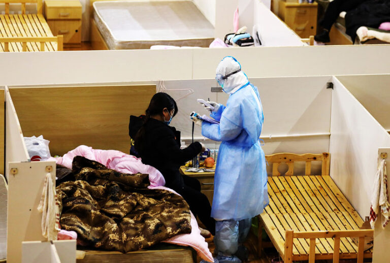 A nurse checks a patient in a temporary hospital for the COVID-19 patients set up in a gymnasium in Wuhan in central China's Hubei province Thursday, March 05, 2020. Most of the patients have been discharged, and only about one hundred are still there. (Feature China/Barcroft Media via Getty Images)