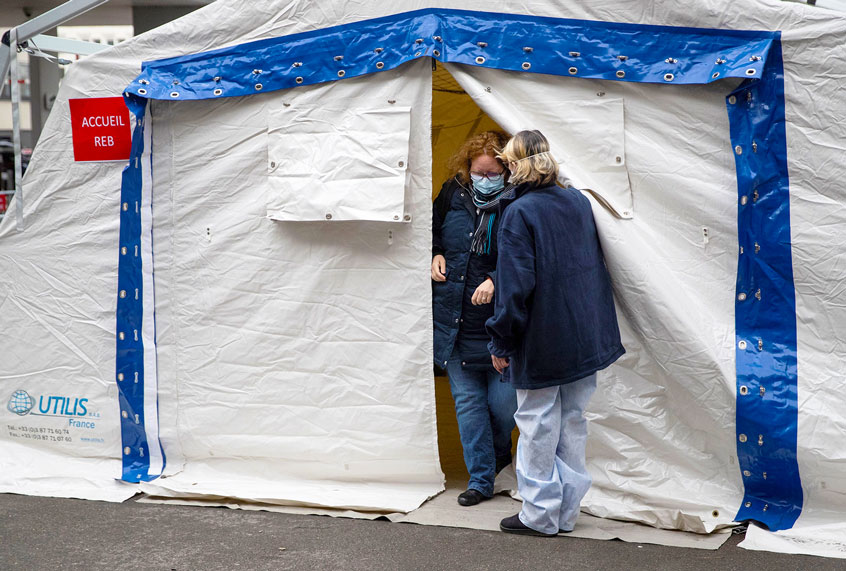 A nurse escorts a patient with covid-19 symptoms to a tent set up in a courtyard of the Henri Mondor Hospital in Creteil, near Paris, on March 6, 2020, to take blood sample as the novel coronavirus strain that erupted in China this year and causes the COVID-19 disease already left nine dead in France and made hundreds ill. (HOMAS SAMSON/AFP via Getty Images)