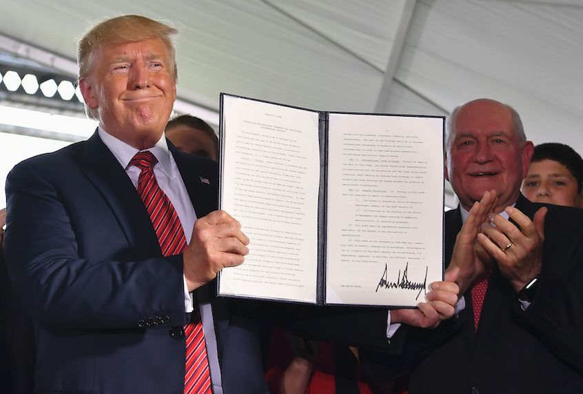 President Donald Trump holds up an executive order to streamline the approval process for GMO crops, as Secretary of Agriculture Sonny Perdue (R) claps following a speech by the president at the Southwest Iowa Renewable Energy ethanol plant in Council Bluffs, Iowa on June 11, 2019. (Mandel Ngan/AFP via Getty)