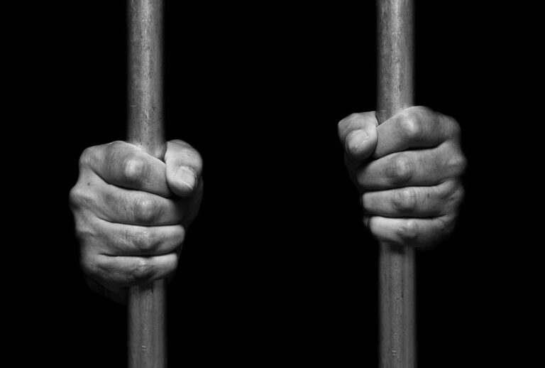 Person's hands holding prison bars (Getty Images)