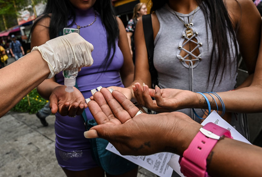 An activist shows sex workers how to apply hand sanitizer during an awareness campaign to promote safe measures against the spread of the new Coronavirus, COVID-19. (Joaquin Sarmiento/AFP via Getty Images)