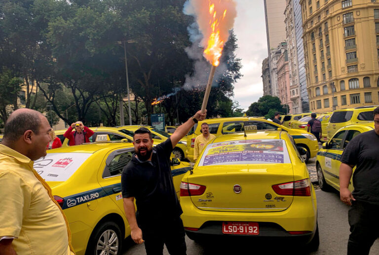 A taxi driver holds a flare during a protest in front of the Rio de Janeiro Municipal Chamber during a protest calling for the approval of a local new law (PLC 78/2018), to impose new rules for rideshare providers like Uber and 99 Taxi, in Rio de Janeiro, Brazil, on October 10, 2019. (MAURO PIMENTEL/AFP via Getty Images)