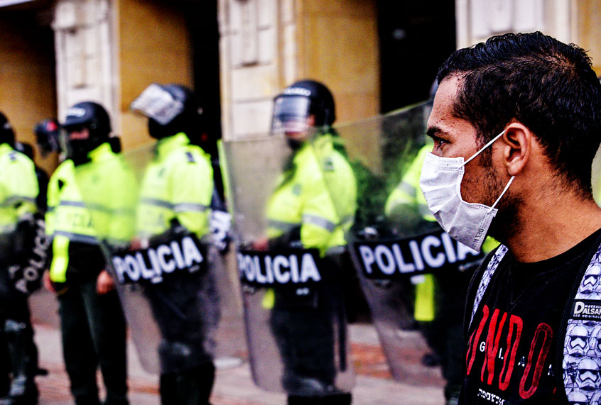 A person wearing a protective mask looks on as homeless, informal vendors, Venezuelan migrants and people displaced by the armed conflict protest demanding humanitarian aid during the COVID-19 quarantine. (Guillermo Legaria Schweizer/Getty Images)