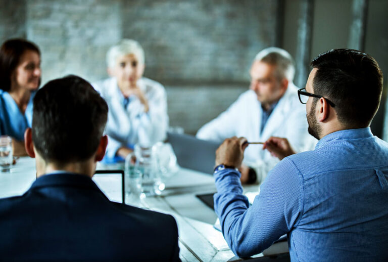 Businessmen having a business meeting with team of doctors at doctor's office. (Getty Images)