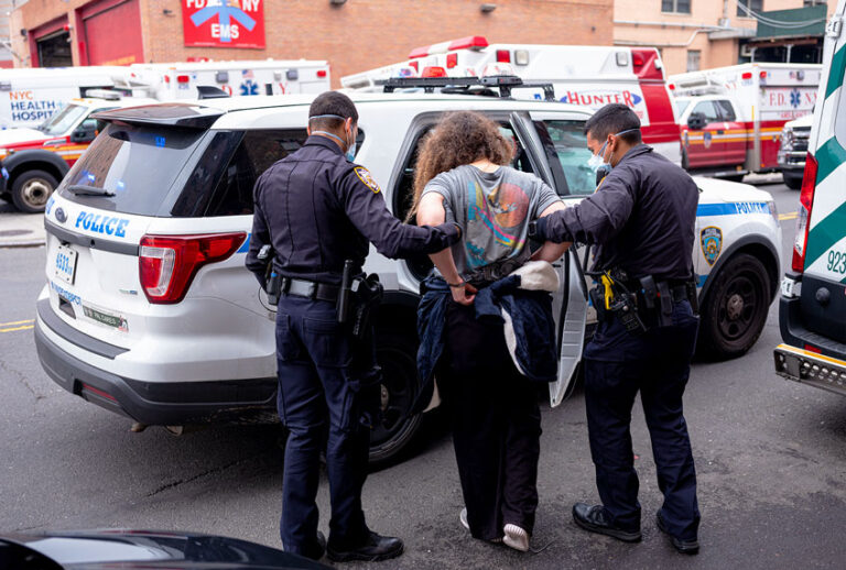 Two officers of the New York Police Department escort a handcuffed woman under arrest to the Emergency Room at the Elmhurst Hospital Center in the Queens borough of New York City (Robert Nickelsberg/Getty Images)