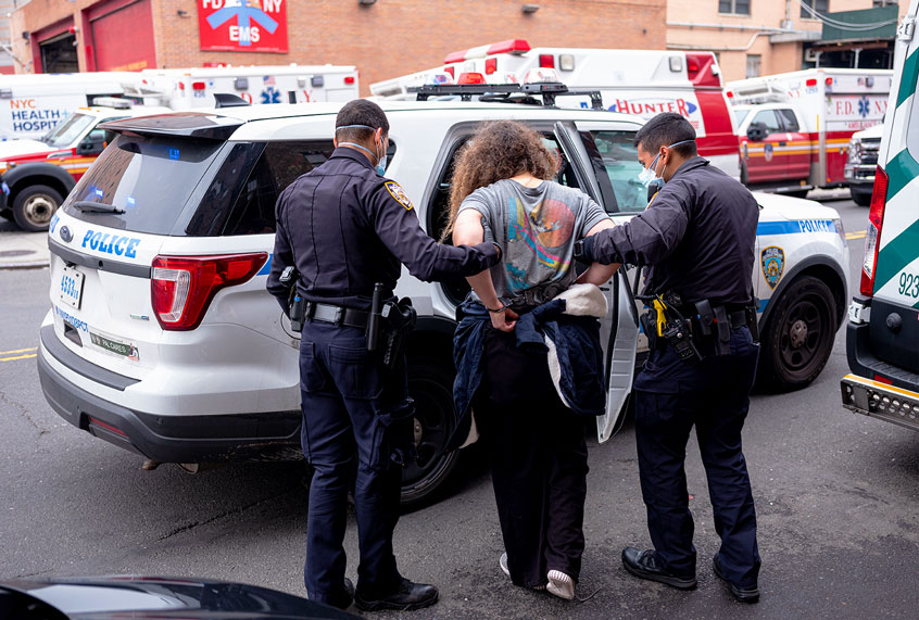 Two officers of the New York Police Department escort a handcuffed woman under arrest to the Emergency Room at the Elmhurst Hospital Center in the Queens borough of New York City (Robert Nickelsberg/Getty Images)