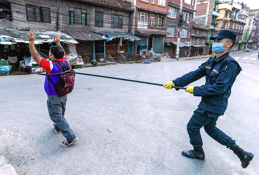 A police officer maintains a safe distance as he detains a man defying the lockdown regulations (Prabin Ranabhat/SOPA Images/LightRocket via Getty Images)