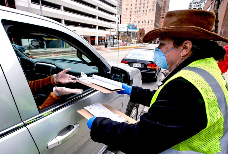 Jill Mickelson helps a drive up voter outside the Frank P. Zeidler Municipal Building Monday March 30, 2020, in Milwaukee. The city is now allowing drive up early voting for the state's April 7 election. (AP Photo/Morry Gash)