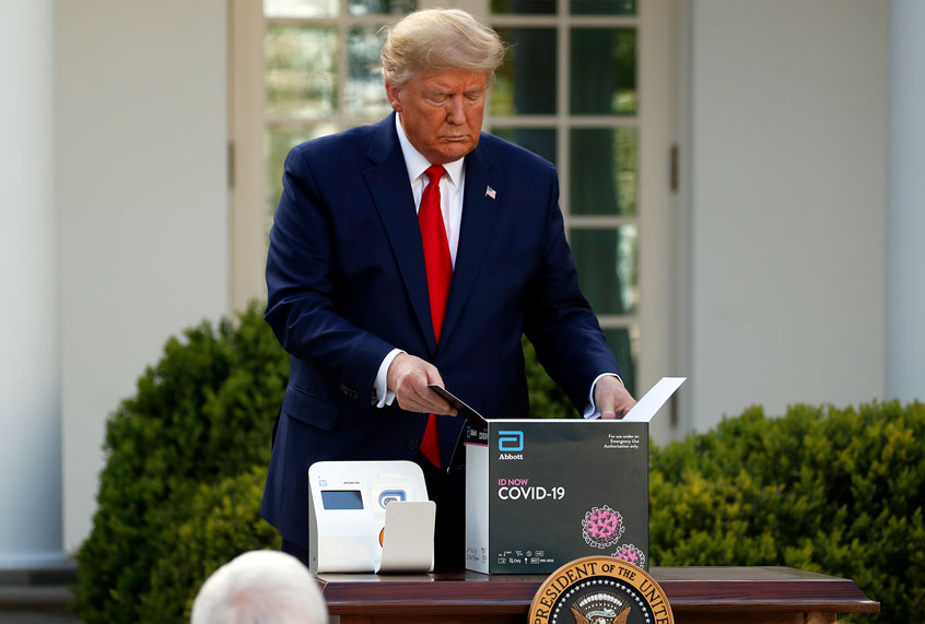 President Donald Trump opens a box containing an Abbott Labs testing kit during a coronavirus briefing at the White House in March. (AP Photo/Alex Brandon)