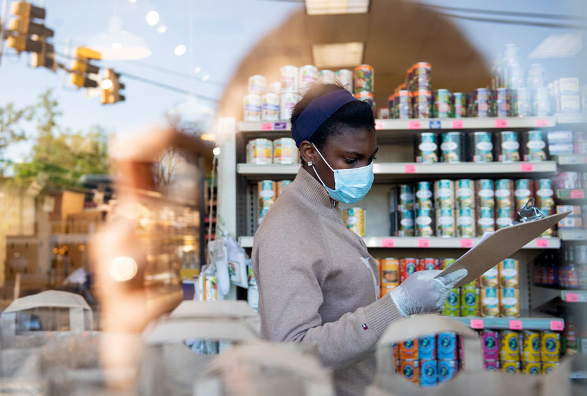 An employee glances at a clipboard as she fulfills grocery orders (Caroline Brehman/CQ-Roll Call, Inc via Getty Images)