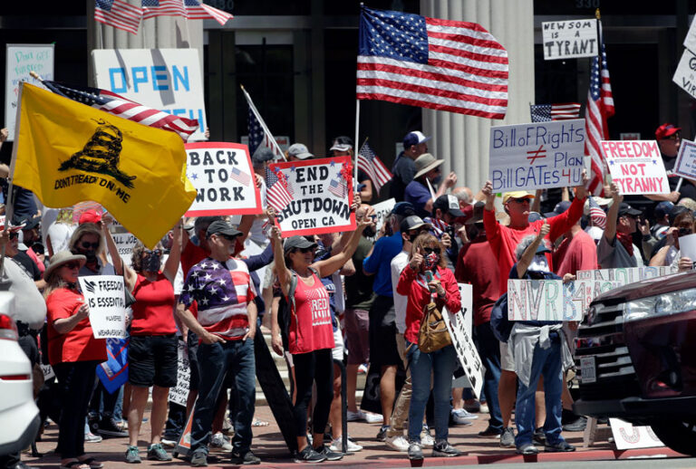 People hold signs and flags during a protest against measures aimed at slowing the spread of the new coronavirus Friday, May 1, 2020, in San Diego. (AP Photo/Gregory Bull)